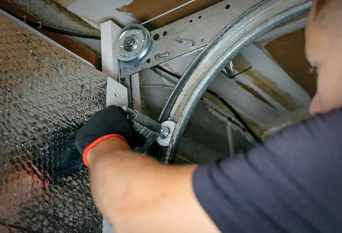 worker attaching rollers to the metal tracks of a garage door during repair